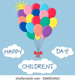 A bunch of multicolored balls with a red bow isolated on the sky background. Clouds and sun. Happy children's day.