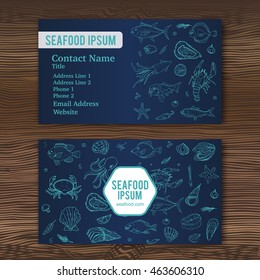 Business card template with hand drawn doodle seafood icons for restaurant. Vector illustration. Cartoon fresh sea food symbols: fish, crab, lobster, oyster, shrimp, shellfish on wood background.