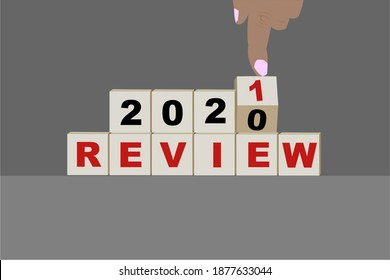 Business concept of planning 2021. Male hand flips a wooden cube and changes the inscription 'Review 2020' to 'Review 2021'. Beautiful grey background, copy space.