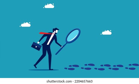 Business detective. businessman uses a magnifying glass to look at footprints 