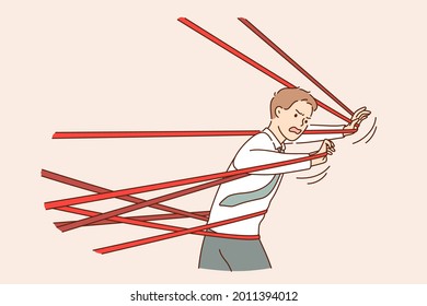 Business difficulty, problem, struggling concept. Angry businessman tied up with red tape trying to run away with full effort and feeing anger rage trying to overcome to reach success 