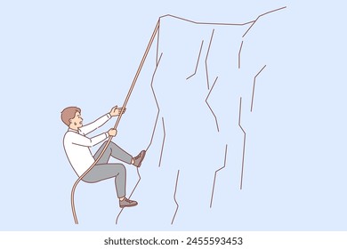Business man climbs up cliff, taking on difficult challenge on career path, and does not stop trying to achieve goal. Challenge for employee tired but moves forward thanks to ambition and motivation