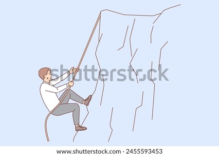 Business man climbs up cliff, taking on difficult challenge on career path, and does not stop trying to achieve goal. Challenge for employee tired but moves forward thanks to ambition and motivation