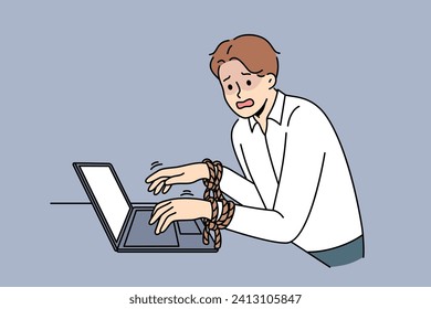 Business man has fallen into slavery from work, and suffers, standing near laptop with hands tied. Concept of career slavery forcing overwork and overtime due to lack of trade union