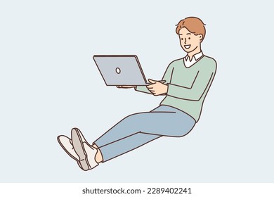 Business man with laptop on lap hovers in zero gravity doing work remotely and communicating with colleagues via Internet. Guy freelancer with laptop works as copywriter or programmer