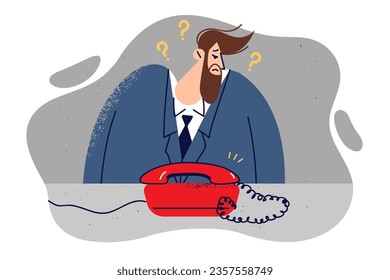 Business man looks at phone during anonymous call and is afraid to pick up phone. Unhappy guy in formal suit is waiting for call from employer after interview, hoping to get good job offer