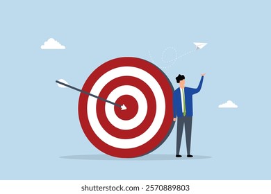 Business objective, assured entrepreneur poses with arrow striking bullseye on archery target. 