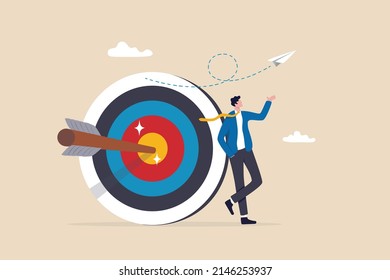 Business objective, purpose or target, goal and resolution to aim for success, aspiration and motivation to achieve goal concept, confident businessman stand with arrow hit bullseye on archery target.