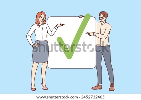 Business partners have completed project show check mark proving completion of assigned tasks. Man and woman office employees striving together to achieve commercial goals and complete project