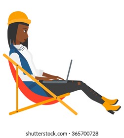 Business woman sitting in chaise lounge with laptop.