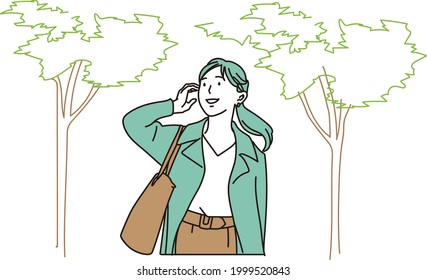 Business woman walking along a row of trees