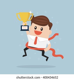 Businessman crossing finish line and holding trophy.