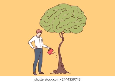 Businessman develops own intelligence by watering trees with brain shaped leaves as metaphor for receiving business education. Guy entrepreneur cares about gaining new knowledge and developing brain