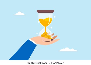 Businessman hand holds hourglass with sand fall into pile of money, illustrating time is valuable and investing for long term to gain profit and earnings. Concept of savings and salary growth