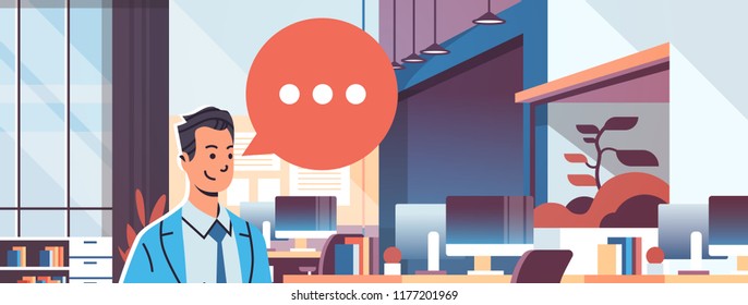 businessman holding tablet speech chat bubble icon over modern workplace cabinet room office interior business man cartoon character portrait flat horizontal banner vector illustration