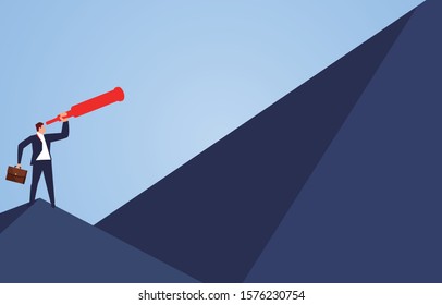 Businessman holding a telescope standing on the top of the mountain looking at the higher mountains