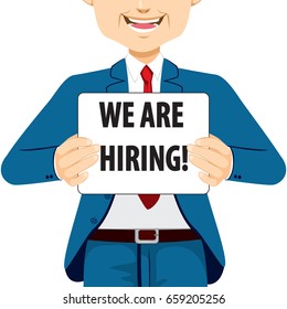 Businessman holding white banner with We Are Hiring text