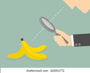Businessman looking to a banana peel through a magnifying glass