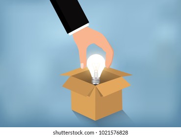 Businessman picked up a light bulb above opened cardboard box. Business concept Have Modern ideas success