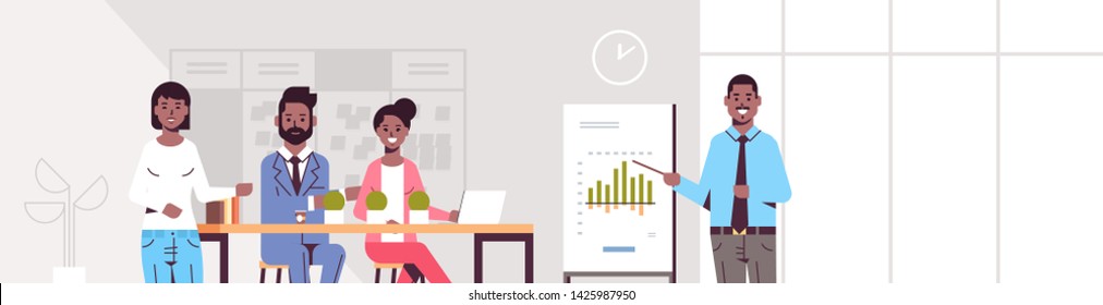 businessman presenting financial graph on flip chart to african american businesspeople team at conference meeting presentation concept modern co-working office interior portrait horizontal