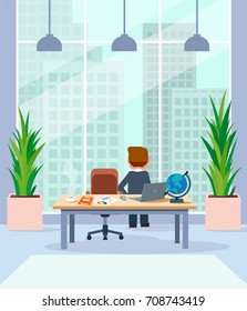 Businessman relaxing standing by his desk in office looking in window at megalopolis city skyline.