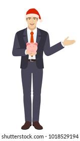 Businessman in Santa hat holding a piggy bank and showing something beside of him. Full length portrait of businessman in a flat style. Vector illustration.