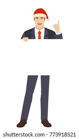Businessman in Santa hat holding white blank poster and pointing up. Full length portrait of businessman in a flat style. Vector illustration.