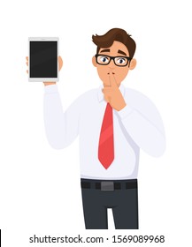 Businessman showing new tablet computer and asking silence. Shut up! Keep quiet! Person is keeping finger on lips. Male character illustration. Modern technology concept in vector cartoon style.