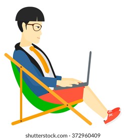 Businessman sitting in chaise lounge with laptop.