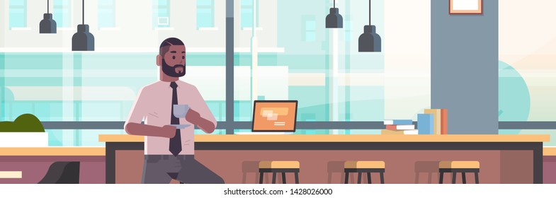 hombre de negocios sentado en una silla en el mostrador de bar con concepto de descanso para ordenador portátil empresario americano africano tomando capuchino café moderno café interior retrato plano horizontal