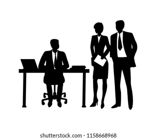 Businessman sitting at table with computer, talking to co-workers.
