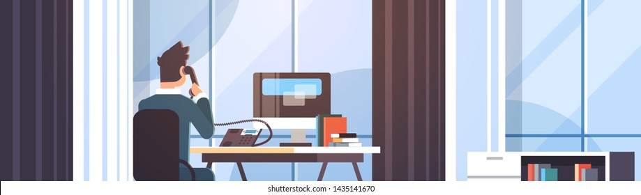 businessman sitting at workplace desk rear view business man using computer while talking on landline phone working process concept creative office interior flat portrait horizontal