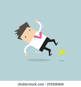 Businessman slipping on a banana peel and falling down