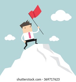  Businessman standing with red flag on mountain peak