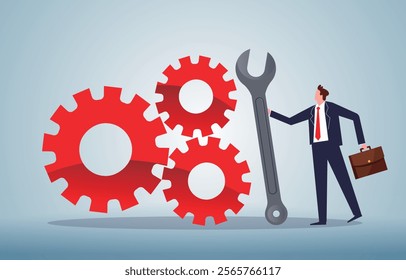 businessman standing with a wrench next to three linked gears