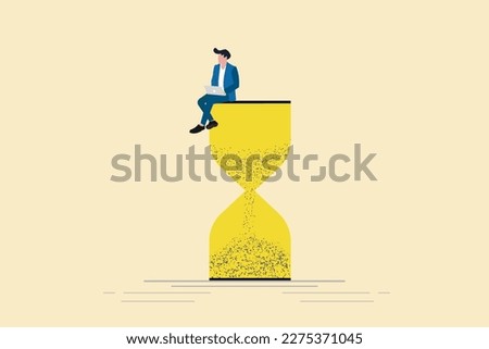Businessman using laptop sitting on an hourglass. Concept of multitasking, productivity and time management