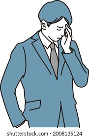 A businessman who is worried while holding his forehead