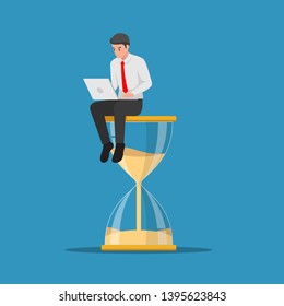 Businessman working with laptop sitting on big hourglass. Time management and deadline concept
