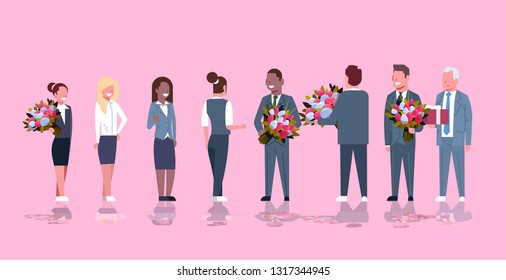 businessmen congratulating businesswomen with happy 8 march womens day concept mix race men giving flowers women pink background full length horizontal