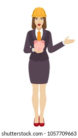 Businesswoman in construction helmet with piggy bank showing something beside of her. Full length portrait of businesswoman in a flat style. Vector illustration.