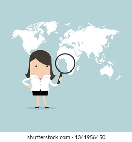 Businesswoman holding magnifying glass finding over world map.