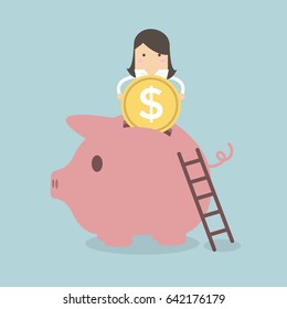 Businesswoman putting coin into piggy bank