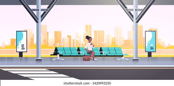 businesswoman sitting modern bus stop african american woman checking time waiting public transport on airport station cityscape background flat horizontal full length