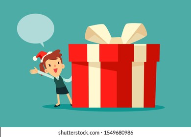 Businesswoman wearing santa claus hat with dialogue bubble standing beside big red christmas gift box with white ribbon. Christmas celebration. Business announcement concept.