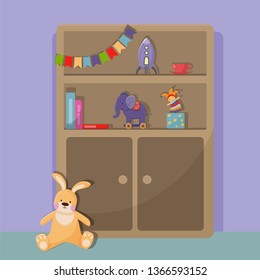 Cabinet with open shelves. On the shelves are children's toys: a cup, a rocket, an elephant with wheels, a clown and a few books. Near the cabinet sits a big bunny