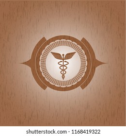 Caduceus medical icon inside badge with wooden background