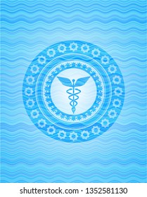 Caduceus medical icon inside light blue water wave style emblem.