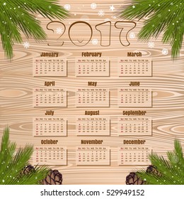 Calendar for 2017 on a wooden background in a frame of fir branches. Christmas design calendar. Vector illustration
