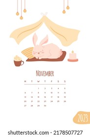 Calendar 2023. November month page design. Cute bunny sleeping at cozy home under the canopy. Candle and hot cocoa drink. Vector illustration with New Year's mascot. Baby rabbit in pink color.