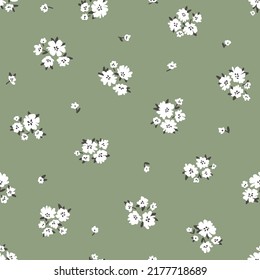 Calico millefleurs seamless pattern. Small white summer wildflowers in a simple hand drawn cartoon style on a green background. Ideal for textile, fabric, surface, wallpaper, scrapbooking, wrapping.